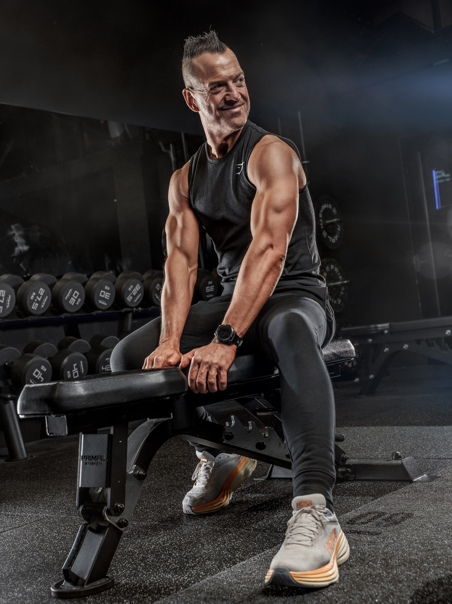 Gareth seated on a bench in a dimly lit gym