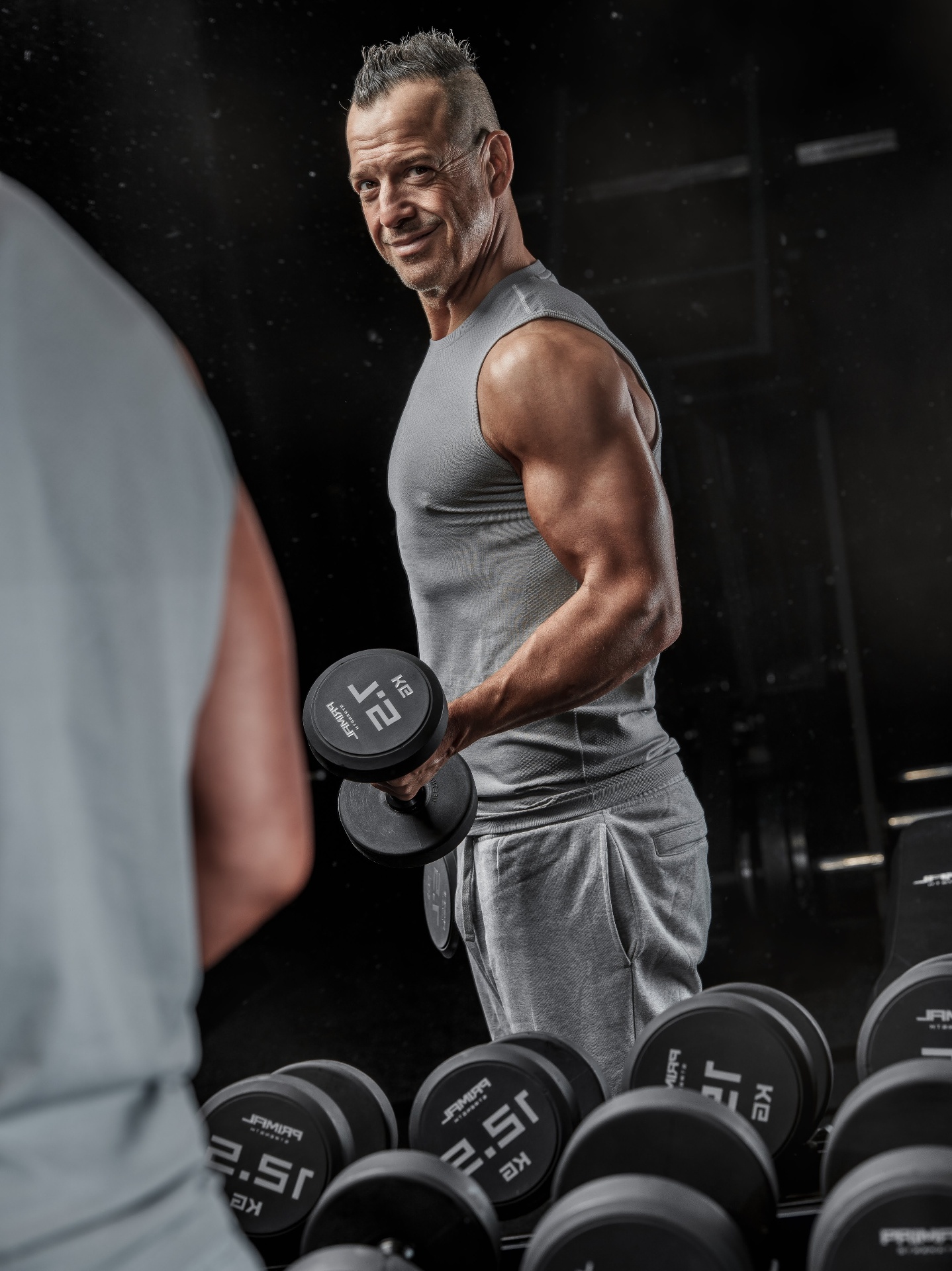 Gareth holding a dumbbell in the gym, looking back with a relaxed expression